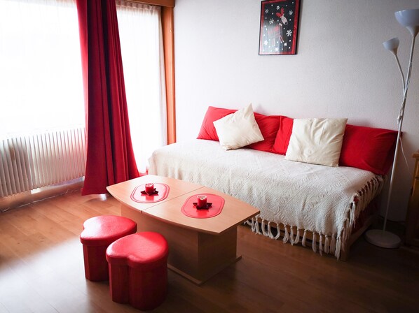 Une pièce chaleureuse avec un lit, une table ornée de deux bougies rouges et un lampadaire rouge.
