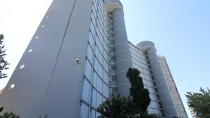 Un edificio moderno con un diseño cilíndrico único, con amplias ventanas y una estructura vertical destacada.