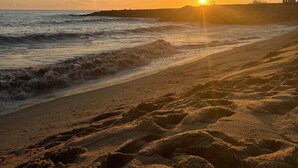 A beach with footprints leading to the water, waves, and a sunset in the background. - Beautiful 3 bedroom townhouse located in Vila Sol in the heart of the Algarve  (Quarteira Vilamoura)