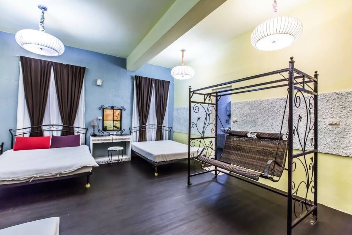 A room with two beds, a desk, and a hanging chair.
