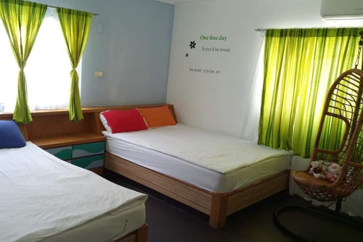 A room with two beds, a wooden bench, a chair, and a wall with a quote.