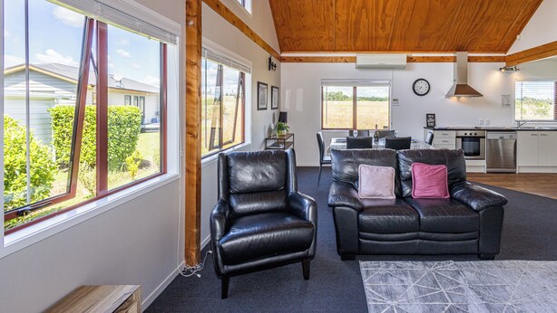 Ein geräumiges Wohnzimmer mit Ledersofas, einem Esstisch und einer Küche im Hintergrund.