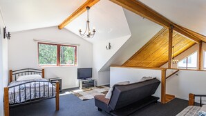 Ein Schlafzimmer mit Schlafgalerie, einem Bett, einer Couch, einem Fernseher und einer Kristallleuchter.