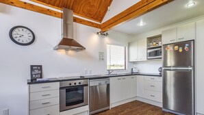 Eine moderne Küche mit Edelstahlgeräten, Holzbalken an der Decke und einem Fenster mit Jalousien.