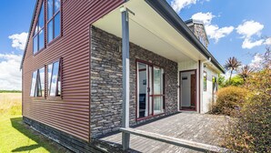 Ein modernes Haus mit Steinverkleidung, großen Fenstern und einer überdachten Veranda.