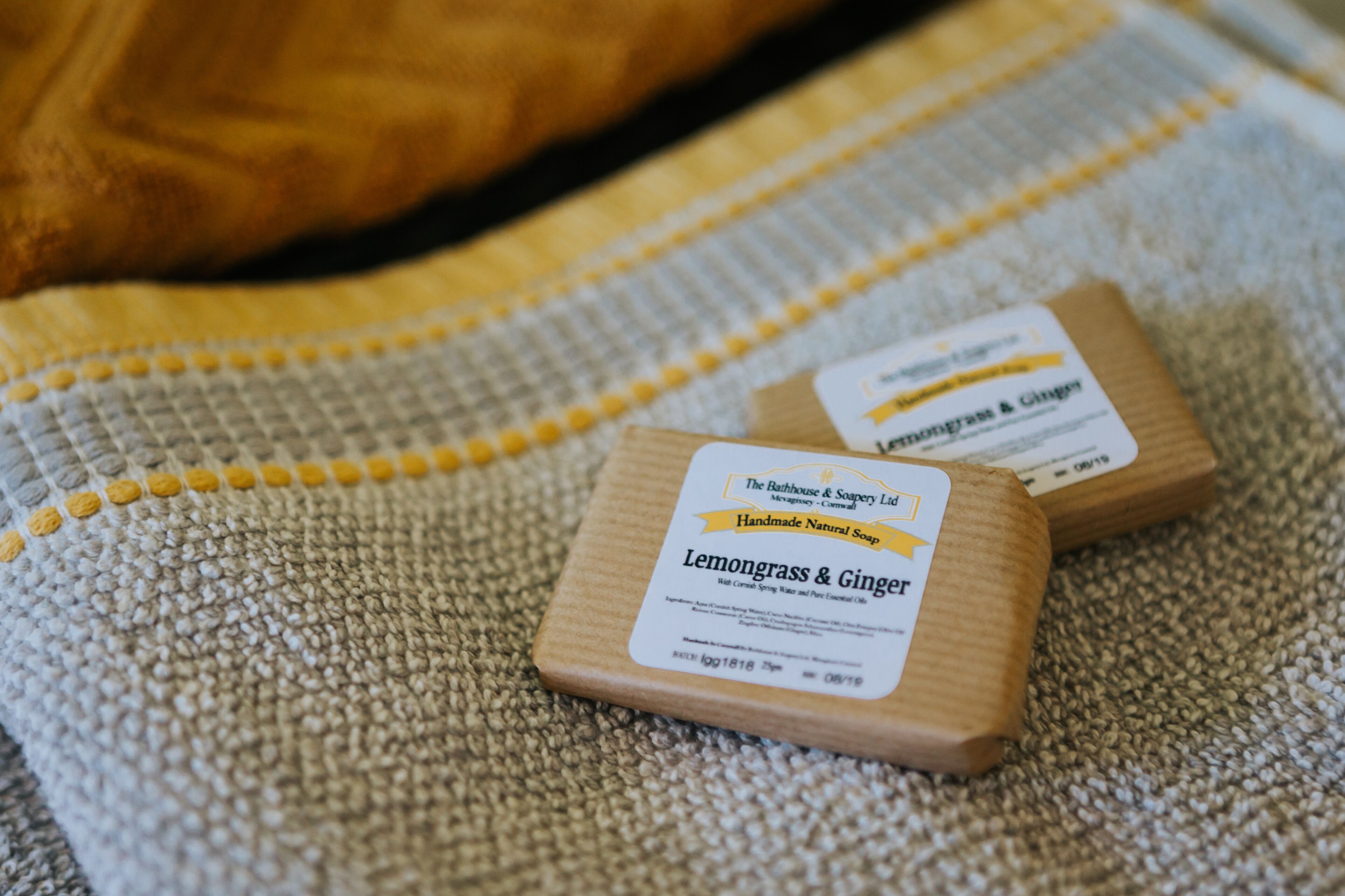 Twee kleine houten doosjes met de aanduiding 'Lemongrass & Ginger' op een stoffen oppervlak met structuur.