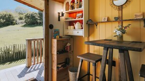 A cozy room with a wooden bench, a table, and shelves with books and decorative items.