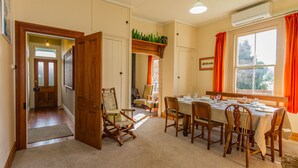 A dining area with a table set for four, surrounded by wooden chairs, a wooden bench, and a small side table. - Kaha Cottage - Rangataua Holiday Home (Ohakune)