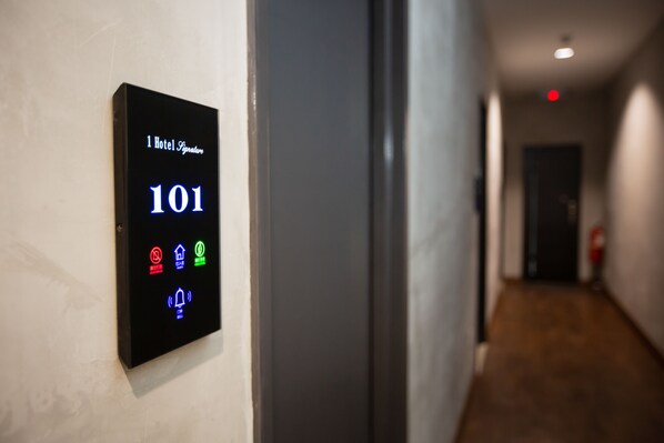 A hallway with a digital sign displaying room number 101 and various icons indicating amenities.