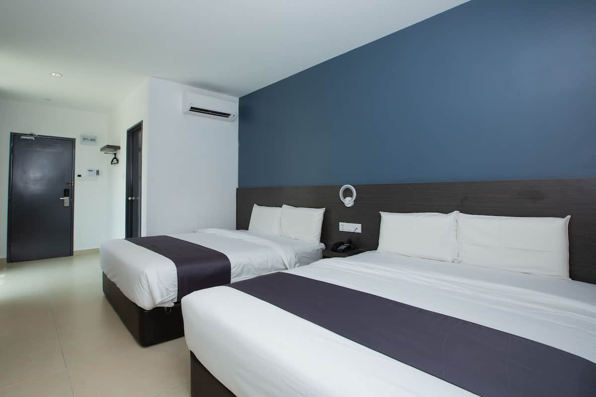 A hotel room with two beds, a dark-colored headboard, white bedding, a wall-mounted phone, and an air conditioning unit.