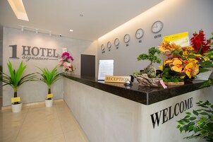 A hotel reception desk with a 'WELCOME' sign, a 'RECEPTION' sign, and clocks displaying times for New York, Paris, Dubai, and London.