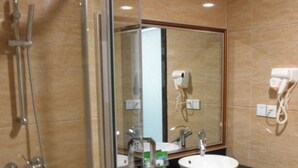 A bathroom with a glass shower enclosure, a sink with a mirror, and a hairdryer on the wall. - Mizparton Hotel (Foshan)