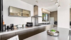 A modern kitchen with a large island, stainless steel appliances, and a window providing natural light.
