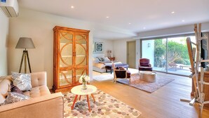 A spacious living room with a sofa, a cabinet, and a dining area.