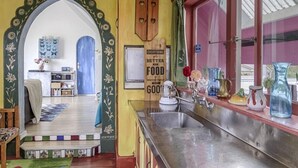 Een keuken met een roestvrijstalen spoelbak, een houten bord en een raam met gordijnen.