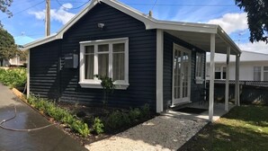 A dark-colored single-story house with a covered porch and a small garden area. - Kokako Lodge Wanganui (Wanganui Township)
