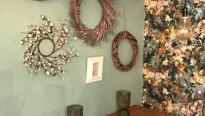 A dining area with a floral wallpaper, a wooden table, and decorative wall hangings including a wreath and a branch with lights. - Kokako Lodge Wanganui (Wanganui Township)