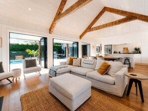 A spacious living room with a large sectional sofa, a dining area, and a kitchen with white cabinetry.