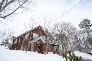 A wooden cabin with a porch and a snow-covered landscape.