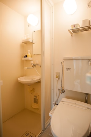 A small, compact bathroom with a toilet, sink, and a mirror.