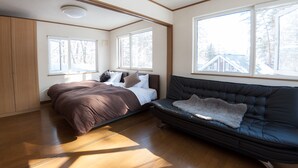 A bedroom with a bed, a sofa, and large windows. - Hakuba Syunrokuan (Hakuba)