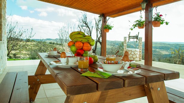 A wooden picnic table set outdoors with a view of the countryside. - Erigone Cottage - Beautiful Ambiance (Vasa)