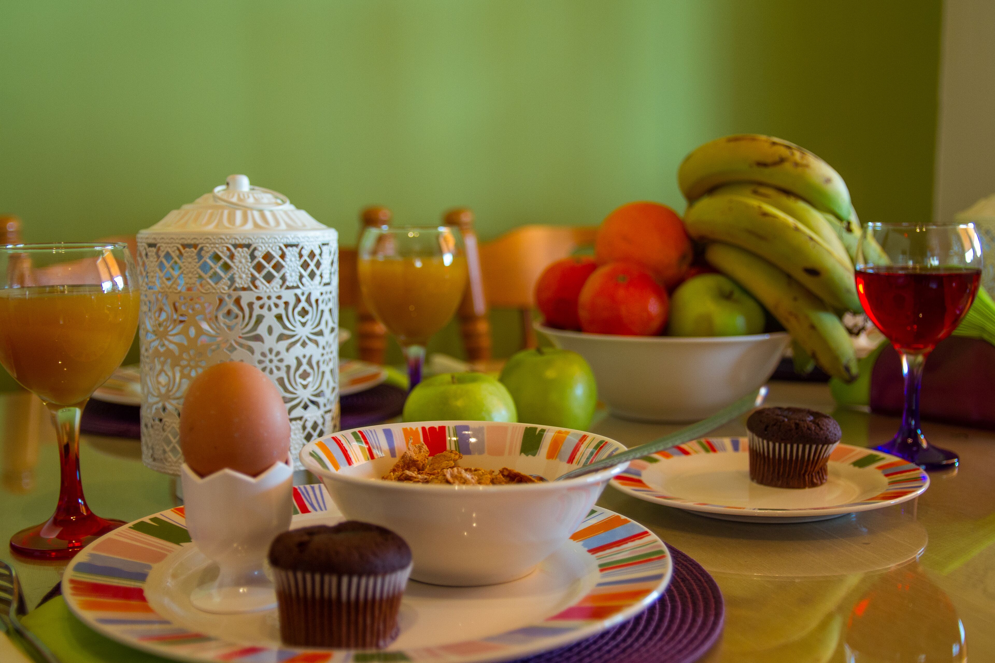 A breakfast table with a variety of food items including fruits, a muffin, and a glass of juice.