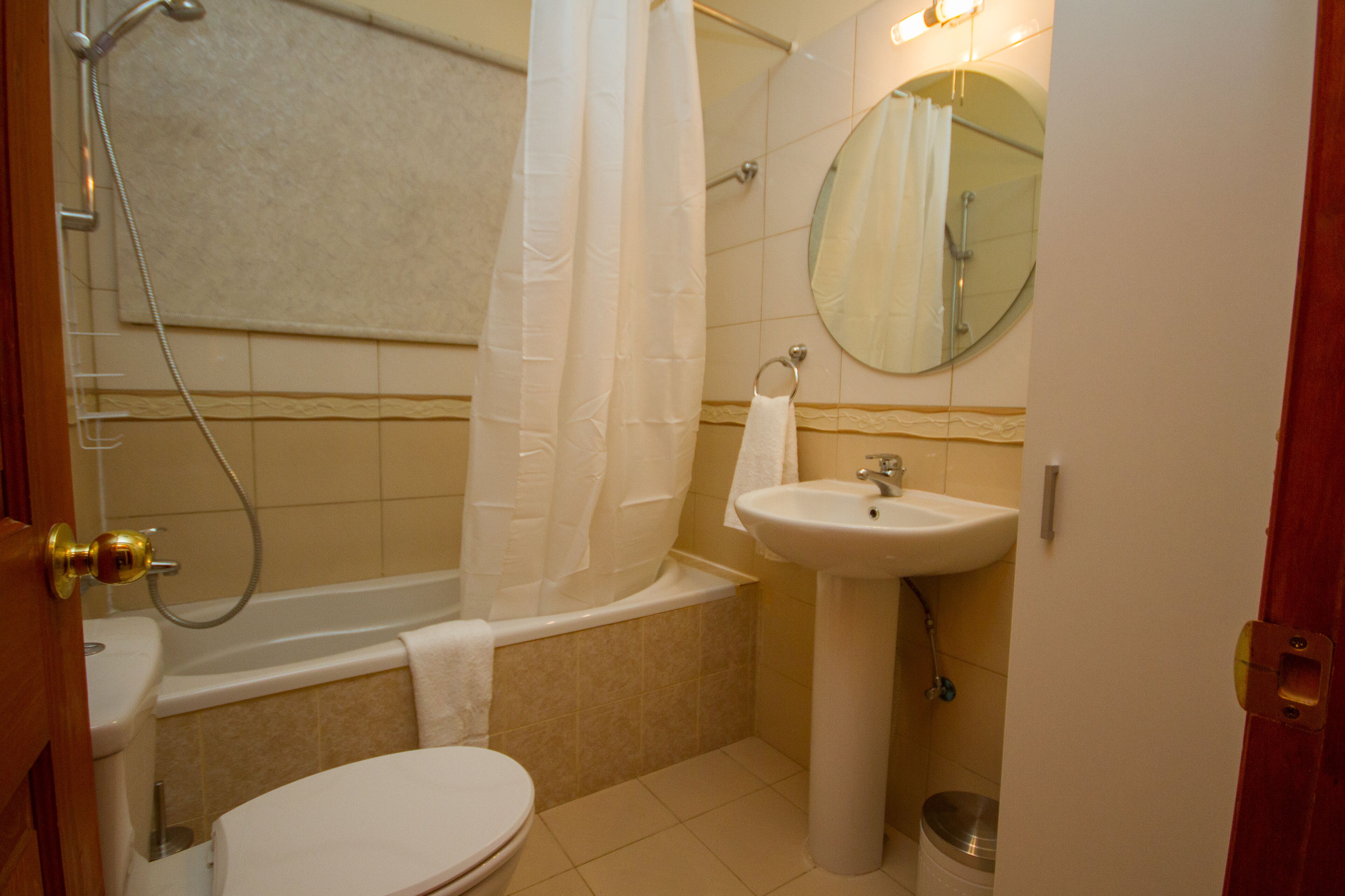 A bathroom with a toilet, sink, bathtub, shower, and a mirror.
