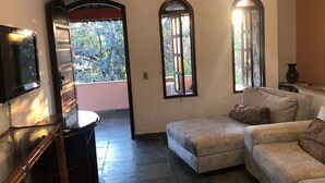 A living room with a sofa, a TV, and a view of the outdoors.