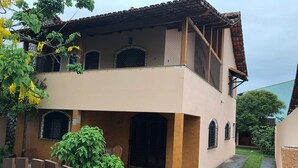 A two-story house with a balcony, a covered porch, and a small garden area.