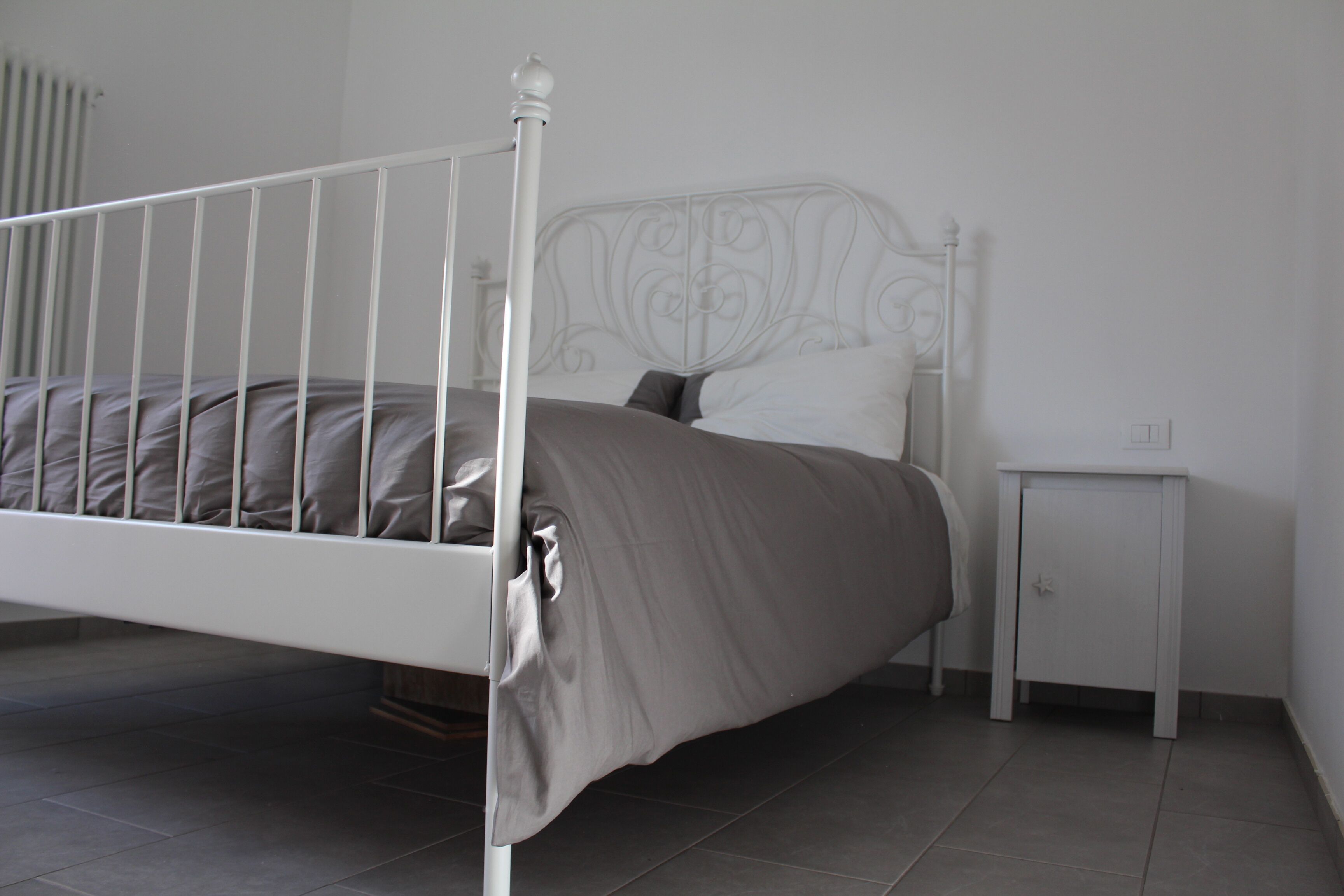 A bed with a metal frame, a bedside table, and a nightstand.