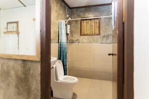 A bathroom with a toilet, a shower curtain, and a window with bamboo blinds. - Higala Hostel Siargao (General Luna)