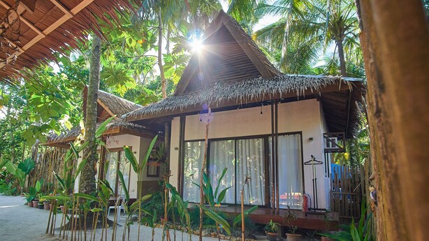A traditional-style building with a thatched roof, surrounded by lush tropical vegetation. - Higala Hostel Siargao (General Luna)