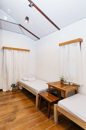 A small, clean room with two single beds, a wooden table, and a bench. - Higala Hostel Siargao (General Luna)
