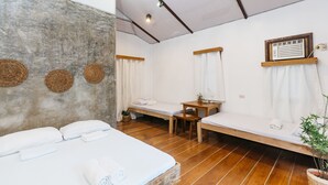 A room with a bed, two benches, a small table, and a potted plant. - Higala Hostel Siargao (General Luna)