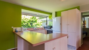 Una cucina moderna con isola centrale, mobili bianchi e una parete verde a contrasto.