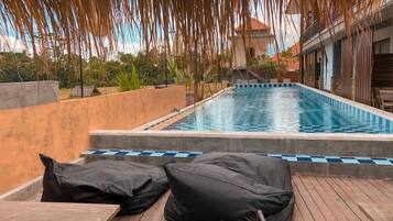 A swimming pool with lounge chairs and a wooden deck.