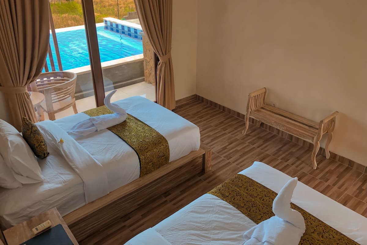 Ein Hotelzimmer mit zwei Betten, Holzboden, Blick auf einen Swimmingpool und einer hölzernen Bank.