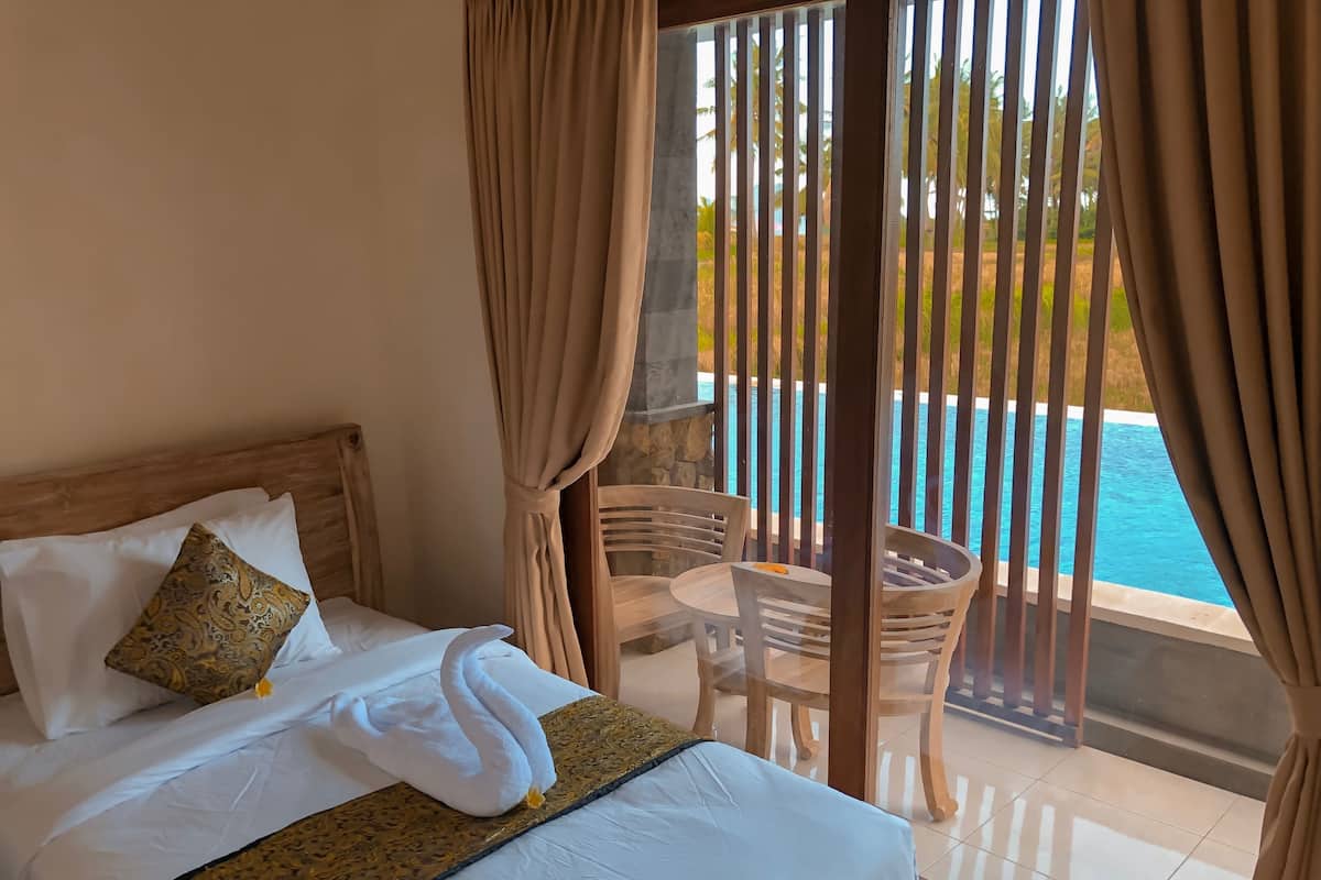 Ein Hotelzimmer mit Bett, Tisch, Stühlen und Blick auf einen Swimmingpool.