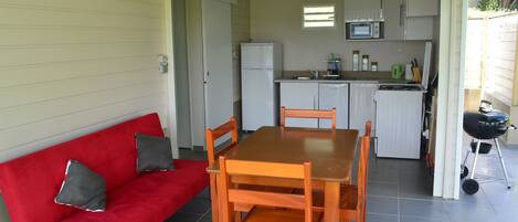 A compact kitchen with a dining area, including a red sofa and wooden table and chairs.