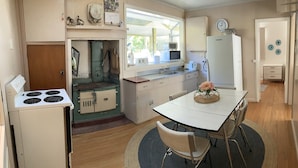 A compact kitchen with a stove, sink, and dining area. - Cissy Bay holiday home (Elaine Bay)