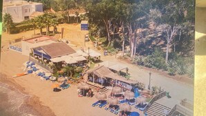 A beachside resort with thatched-roof structures, sun loungers, and a sign reading "VICTORS BEE". - BEACHFRONT , Central,  quiet,  parking,  pool (Marbella)