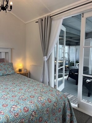 Un dormitorio con una cama, una mesita de noche, una lámpara y vistas a una terraza exterior.