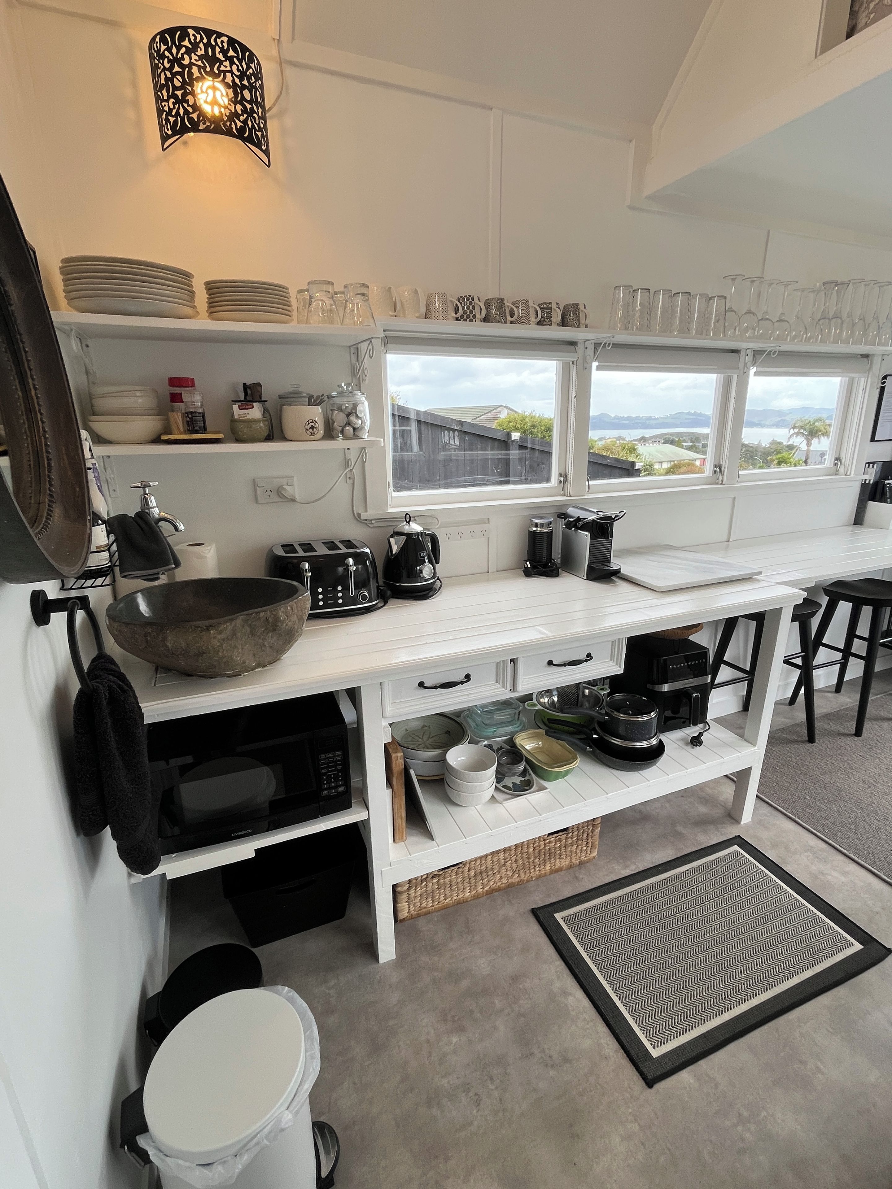 A kitchen with white cabinetry, a black kettle, and a window overlooking a landscape.
