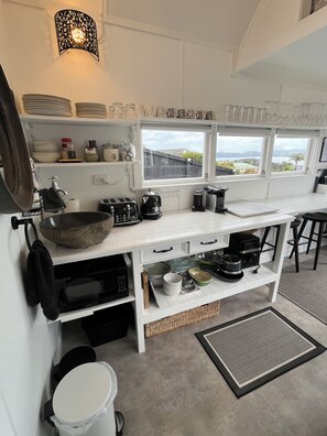 Cocina con armarios blancos, un hervidor negro y ventana con vista al paisaje.