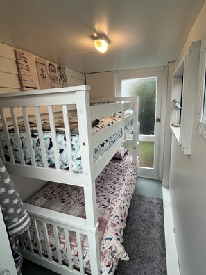 A room with bunk beds, a door leading outside, and a small window.