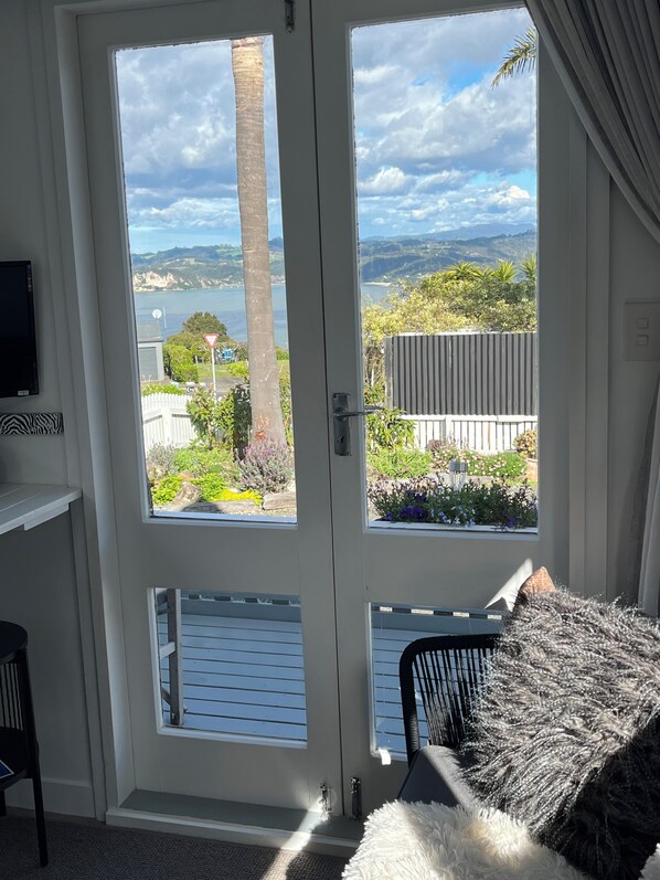 Una habitación con una puerta que da a un balcón con vistas a un lago y colinas.