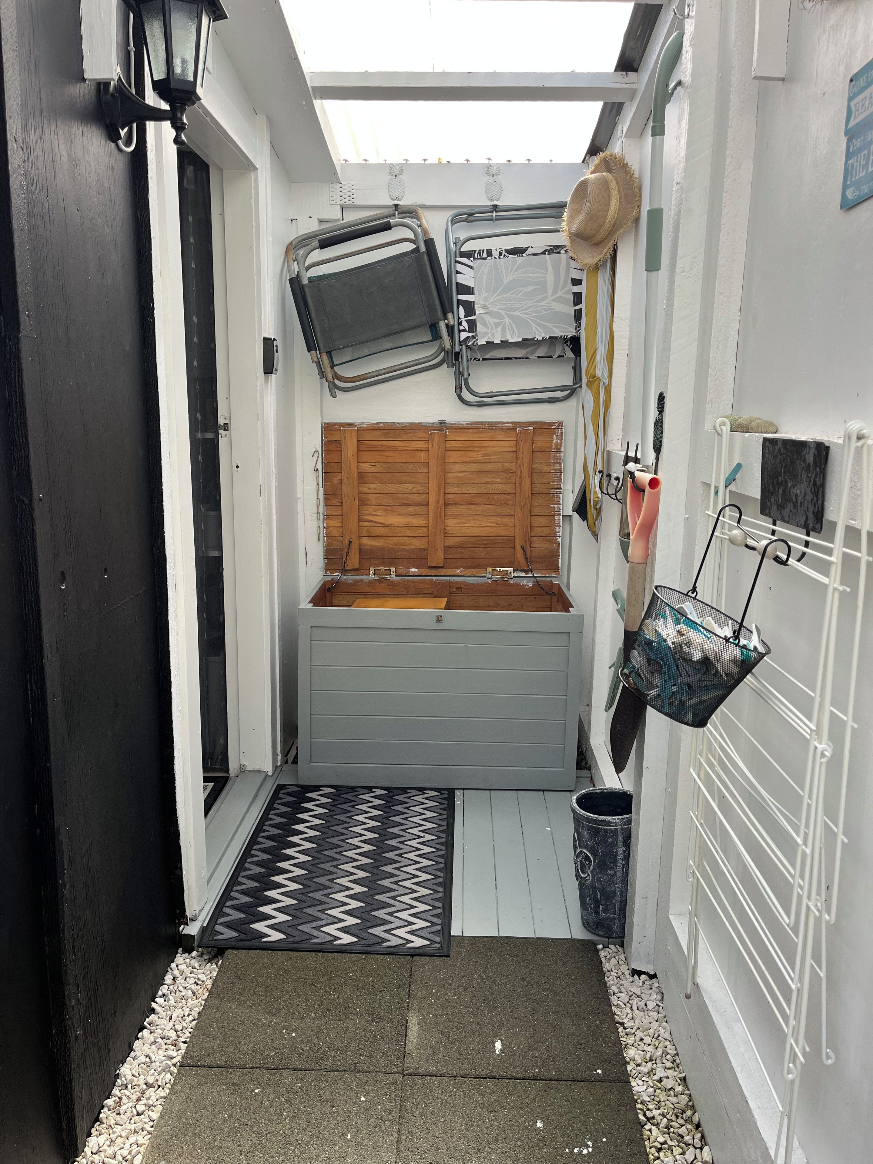 A compact storage area with a bench, a metal rack, and a hat hanging on the wall.