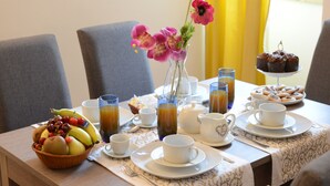 A breakfast table with a fruit bowl, coffee cups, a vase with flowers, and a plate of muffins. - Vacation House Zagara - Giardinello (Giardinello)