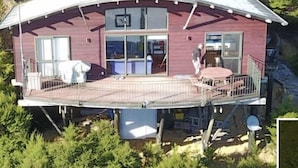 A two-story house with a balcony, large windows, and a covered outdoor area. - Peaceful Ocean facing Island Escape (Kawau Island)